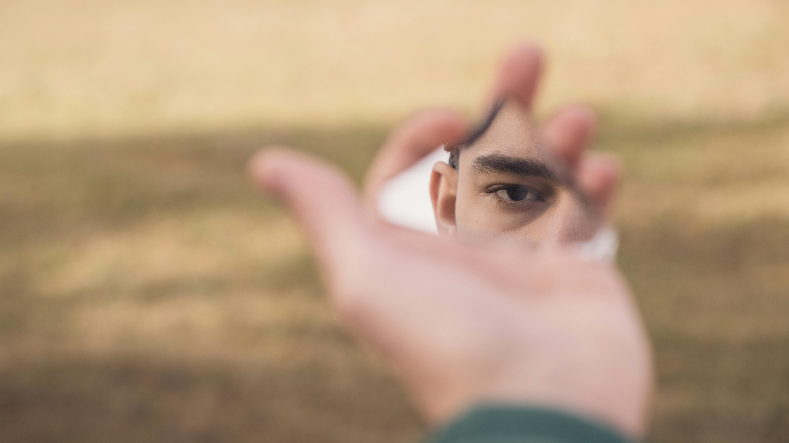 Eine Hand hält einen zerbrochenen Spiegel, in dem sich ein verzerrtes Spiegelbild zeigt – als Symbol für die Frage, ob ein Narzisst weiß, dass er ein Narzisst ist.